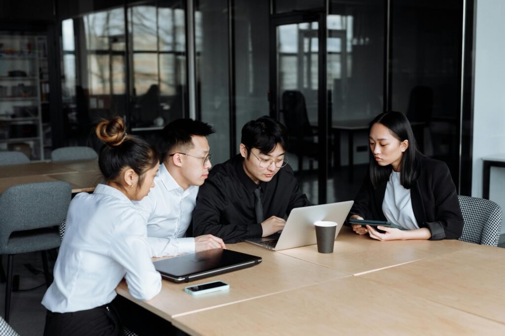 Group of professionals collaborating at a modern office table with laptops.